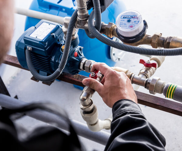 Technician checking water system nodes. Modern Industrial background.